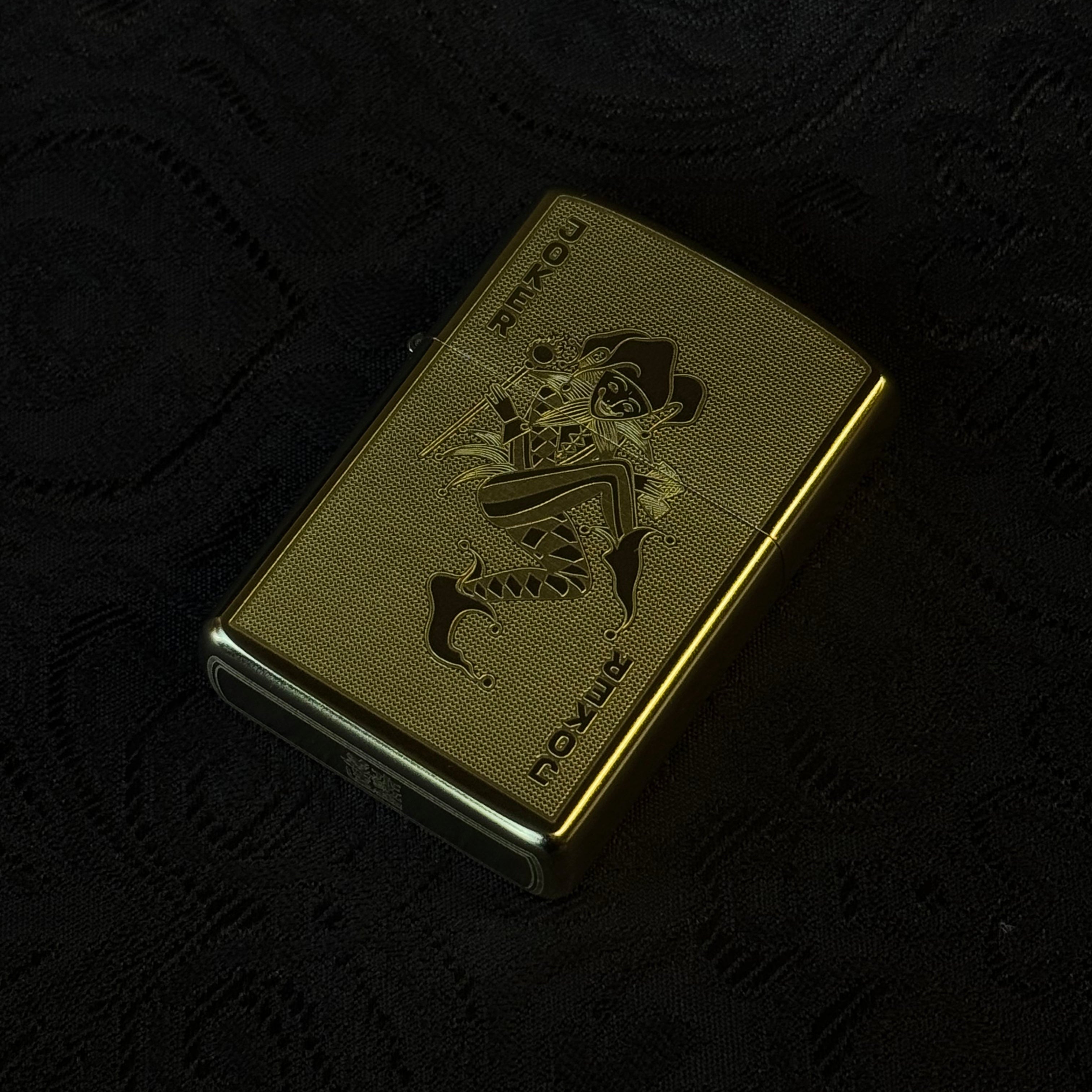 Gold lighter with a brand logo on a black textured background